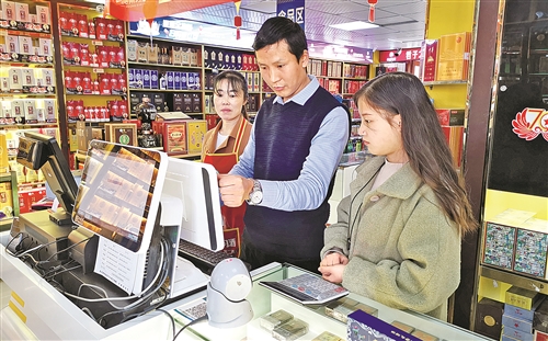 贵阳市修文县零售客户詹镇源（中）在指导店员使用卷烟店铺管理系统